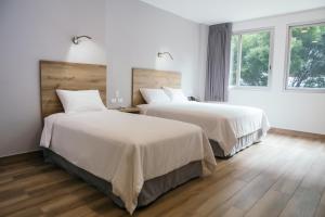 Duas camas num quarto com paredes brancas e pisos de madeira em The Park Hotel em Guayaquil