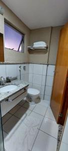 baño con aseo y lavabo y ventana en Golden Dolphin Roberto Imóveis, en Caldas Novas