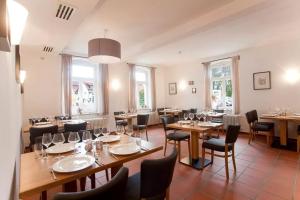 un restaurante con mesas y sillas de madera y ventanas en Gasthaus zum Halbmond, en Speyer
