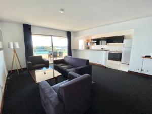 a living room with a couch and chairs and a kitchen at Casa Del Sole Apartments in Noumea