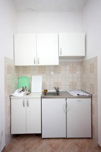 eine Küche mit weißen Schränken und einem Waschbecken in der Unterkunft Apartments by the sea Polace, Mljet - 613 in Polače