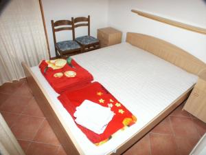 a small bed with a red blanket and two chairs at Apartments by the sea Pomena, Mljet - 614 in Pomena