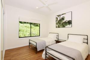 2 camas en una habitación con ventana en Rainforest River Retreat Kangaroo Valley, en Upper Kangaroo River