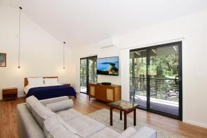 sala de estar con sofá y cama en Rainforest River Retreat Kangaroo Valley, en Upper Kangaroo River