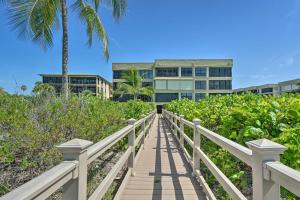 a boardwalk leading to a building with a palm tree at Luxury Sanibel Condo with Ocean View Steps to Beach in Sanibel