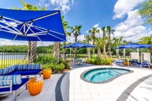 a patio with blue umbrellas and a swimming pool at New Lovely Home at Sonoma Resort at Tapestry in Kissimmee