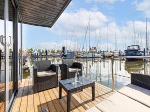 a porch with chairs and a table on a marina at Comfortable houseboat in Marina Volendam in Volendam