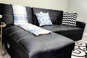 um sofá de couro preto com almofadas em cima em QUIET & COZY MODERN SUITE CLOSE TO RCMP em Regina