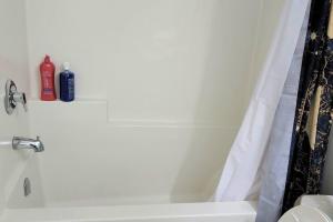 a bathroom with a white tub and a shower at QUIET & COZY MODERN SUITE CLOSE TO RCMP in Regina