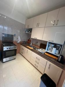 Una cocina con gabinetes blancos y un horno de estufa. en Magnifique appartement proche Arribat Center, en Rabat
