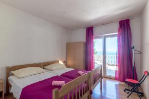 een slaapkamer met een bed met paarse lakens en een raam bij Seaside secluded apartments Cove Torac, Hvar - 575 in Gdinj