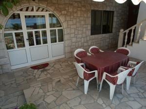 un patio con mesa, sillas y pared de piedra. en Apartments by the sea Sucuraj, Hvar - 590, en Sućuraj