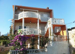 una casa con balcones blancos y flores púrpuras en Apartments by the sea Sucuraj, Hvar - 590, en Sućuraj