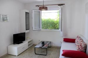 uma sala de estar com um sofá, uma televisão e uma janela em Apartments by the sea Mudri Dolac, Hvar - 582 em Vrboska