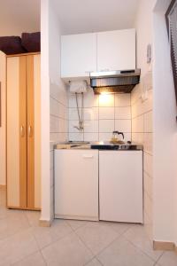una cocina con armarios blancos y fregadero en Family friendly apartments with a swimming pool Stari Grad, Hvar - 583 en Stari Grad
