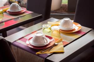 a table with plates and cups and utensils on at Hotel Cote Patio in Nîmes