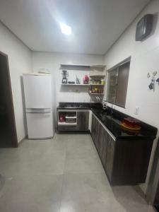 a kitchen with a white refrigerator and a sink at Casa em ALTER DO CHÃO 3 QUARTOS in Alter do Chao