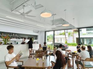 a group of people sitting at tables in a restaurant at Joy Villa Đại Lải - 5 phòng ngủ in Phúc Yên