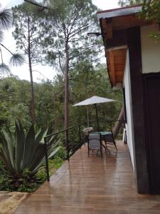 un balcone di una casa con tavolo e ombrellone di Mazamitla Pinos del Rio a Mazamitla