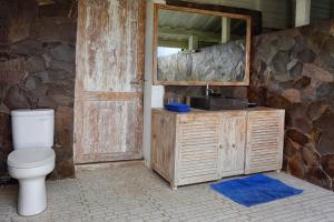 a bathroom with a toilet and a mirror and a door at Gili Eco Villas in Gili Trawangan