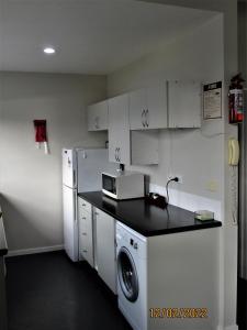 a kitchen with a microwave and a washer and dryer at Spectacular Lake & Mountain Views in Queenstown