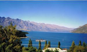 a boat in a large body of water with mountains at Spectacular Lake & Mountain Views in Queenstown