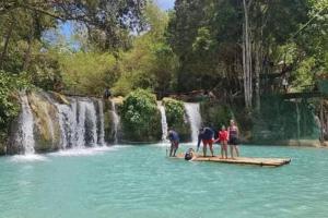 a group of people standing in the water near a waterfall at LightHaus DP Garden Resort in Siquijor