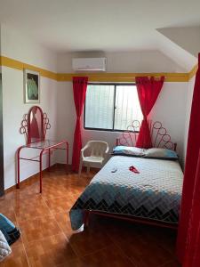 - une chambre avec un lit doté de rideaux rouges et d'une fenêtre dans l'établissement Finca del profe, à Santa Fe de Antioquia