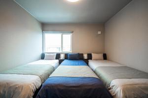 uma fila de camas num quarto com uma janela em THE SUN LOUNGE em Kushiro