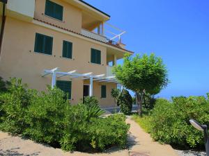 ein Gebäude mit grünen Fensterläden und einem Baum in der Unterkunft Belvilla by OYO Bottone in Parghelia