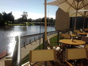 a restaurant with tables and chairs next to a river at Benalla Apartments in Benalla