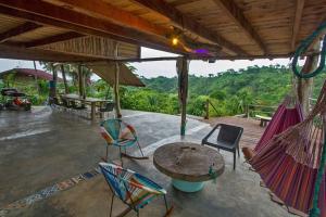 a patio with chairs and a table and hammocks at Elemental lodge in Santa Marta