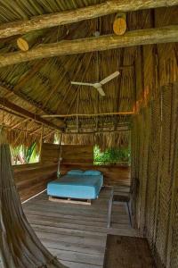 a bed in a straw hut with a clock on the ceiling at Elemental lodge in Santa Marta