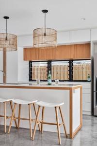 a kitchen with two stools and a counter in a kitchen at Sanctuary Spaces - Lomani Eleven in Byron Bay