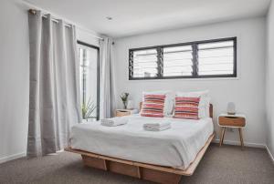 um quarto com uma cama com duas almofadas e uma janela em Sanctuary Spaces - Lomani Eleven em Byron Bay