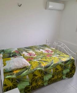 a bed with a colorful comforter on it at Logement Campagne Coquelicots Plaisance in Le Lamentin