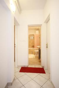 - un couloir avec une salle de bains pourvue d'un tapis rouge dans l'établissement Apartment Viganj 633c, à Viganj