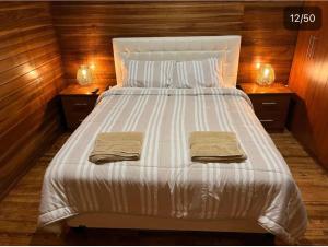 a large white bed with two towels on it at Mi Margarita Chalets in Alausí