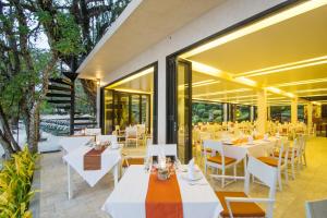 ein Restaurant mit weißen Tischen, Stühlen und Fenstern in der Unterkunft SYLVAN Koh Chang in Ko Chang