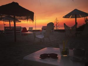 a table and chairs on the beach with a drink at Rock’s Beach Spot Suit in Costa da Caparica
