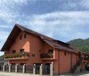 a large orange building with two balconies and a fence at Four S Palace in Băile Borşa