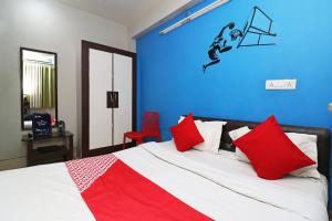 a bedroom with a bed with red pillows and a blue wall at OYO Sher E Bengal in Durgāpur