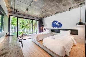 a bedroom with two beds and a large window at Kokotel Khao Lak Lighthouse in Khao Lak