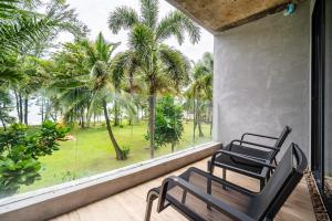 two chairs on a balcony with a view of palm trees at Kokotel Khao Lak Lighthouse in Khao Lak