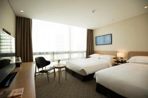 Best Western Haeundae Hotel في بوسان: غرفة فندقية بسريرين ومكتب