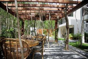 a patio with a table and chairs under a pergola at Lumina at Looltum Tulum in Tulum