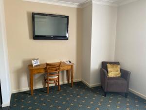 a room with a desk and a television on the wall at 503 On Princes Drive Motel in Morwell