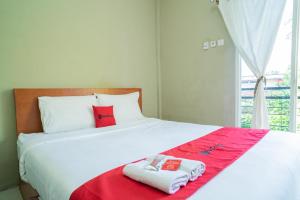 een slaapkamer met een bed met twee handdoeken erop bij RedDoorz Plus Syariah At Lotus Hotel Bojonegoro in Bojonegoro