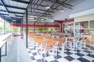 een restaurant met houten tafels en stoelen op een geruite vloer bij RedDoorz Plus Syariah At Lotus Hotel Bojonegoro in Bojonegoro