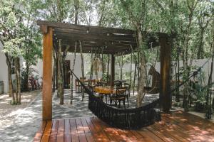 a wooden pergola with a table and chairs on a patio at Lumina at Looltum Tulum in Tulum